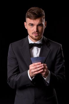 man in a suit posing with cards for gambling on black background