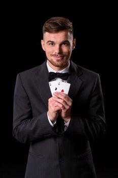 man in a suit posing with cards for gambling on black background