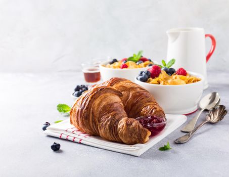 Croissants, corn flakes and berries on light gray background. Copy space. Healthy breakfast concept.