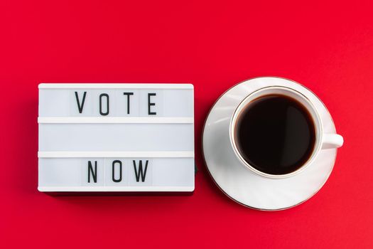 Vote now. Sign and cup of coffee on a red background. Election voting concept.