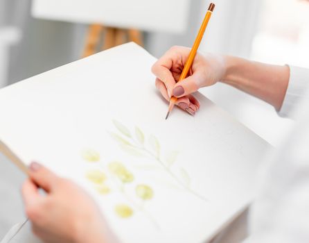 Woman hands holding white canvas paper and graphic pencil and drawing sketch