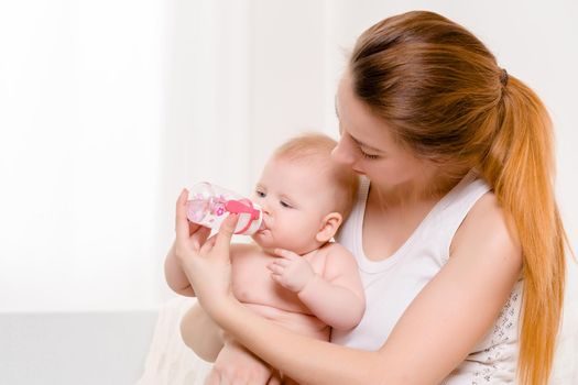 Feeding Baby. Baby eating milk from the bottle. Mother Feeds Her Newborn Baby