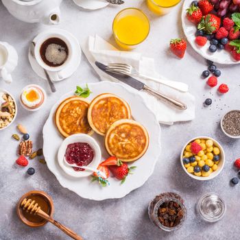 Healthy breakfast with fresh hot pancakes with berry jam on light gray background, top view.