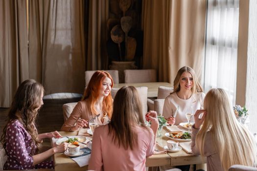 Five women. Portrait of young people having breakfast at table in restaurant.