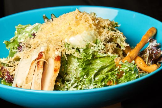 Blue bowl of Caesar salad with chicken sous-vide.