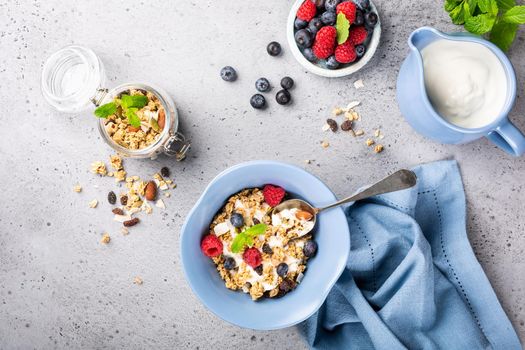 Healthy food background with homemade oatmeal granola or muesli with yogurt and fresh berries for healthy morning breakfast, top view, copy space.