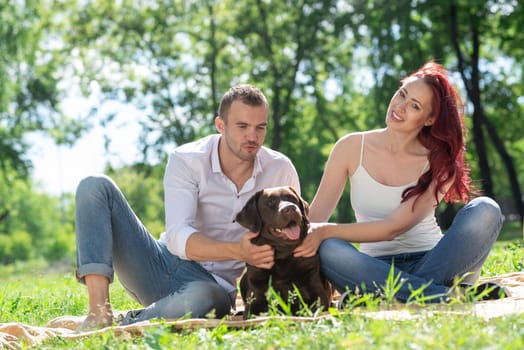 A couple and their dog in the park. Spending time with friends