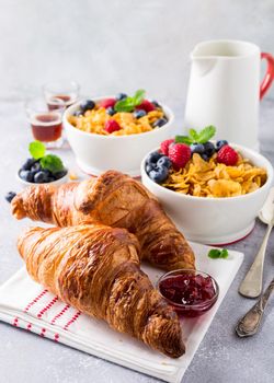 Croissants, corn flakes and berries on light gray background. Copy space. Healthy breakfast concept.