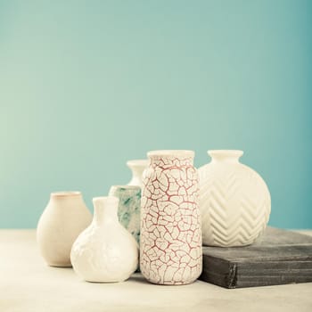 Home decor - various light colored vases on gray concrete background against blue wall. Copy space, retro style toned.