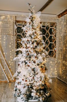 Beautifully decorated Christmas tree and lots of glowing garlands and light bulbs. Preparing for the Christmas party at home.