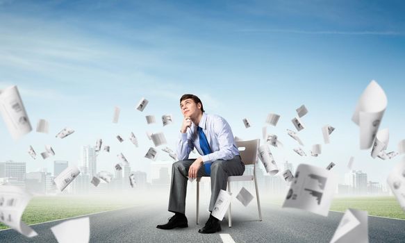 young businessman sits on an office chair, thoughtful and looking up