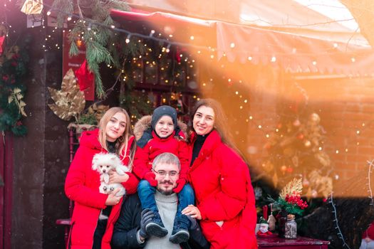 Happy family on the porch of the Christmas decorated house, snowing outdoor. Happy New Year and Merry Christmas. Magic winter