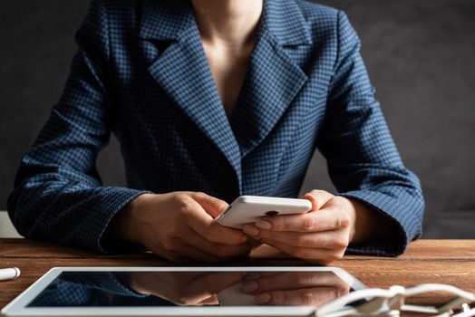 Businesswoman using mobile phone at desk. Close up woman hands and tablet computer. Mobile communication concept with chatting woman. Digital technology in strategy planning and company management