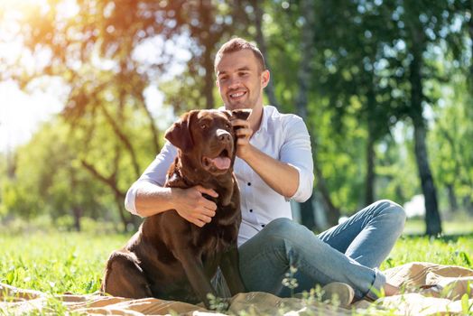 Young man hugs a dog. Spending time with friends in the park