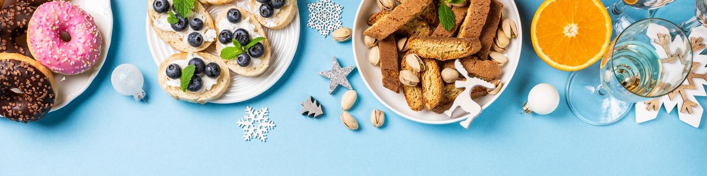 Overhead shoot of Chtistmas holiday food concept background with dinner party table over blue, top view, flat lay with copy space, banner