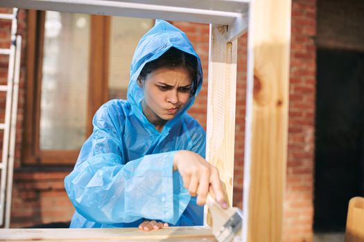 cheerful woman house painter in protective suit repairing home. High quality photo