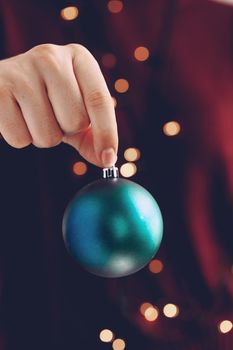 Female hand holding a Christmas ball close up, festive background