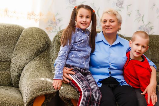 Grandmother and grandchildren sitting together on sofa in living room