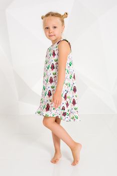 Beautiful little fashion model on white studio background. Portrait of cute girl posing in studio. Little blonde in bright summer dress