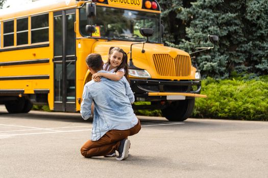 Girl with father going back to school near the school bus