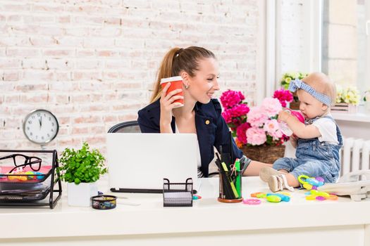 Businesswoman mother woman with a daughter working at the computer. At the workplace, together with a small child