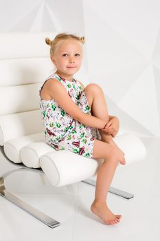 Beautiful little fashion model on white studio background. Portrait of cute girl posing in studio. Little blonde in bright summer dress