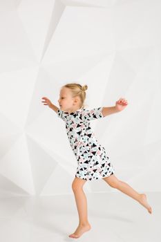 Beautiful little fashion model on white studio background. Portrait of cute girl posing in studio. Little blonde in bright summer dress