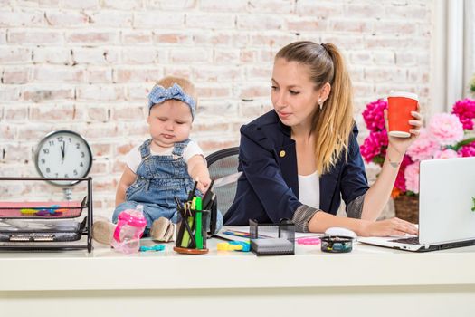 Businesswoman mother woman with a daughter working at the laptop. At the workplace, together with a small child