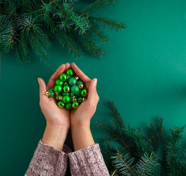 Christmas green background. Pine branches, needles and Christmas tree. View from above. Nature. December mood Green balls keep in hands. Decorated. Copy space.