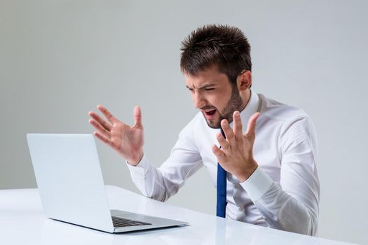 the young man is nervous. It uses a computer while sitting at a table. Office clothing