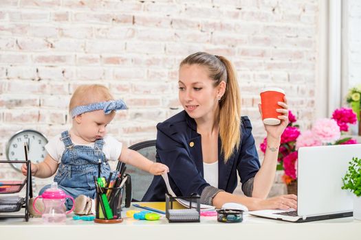 Businesswoman mother woman with a daughter working at the laptop. At the workplace, together with a small child