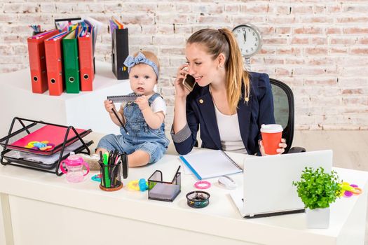 Family Business - telecommute Businesswoman and mother with kid is making a phone call. At the workplace, together with a small child