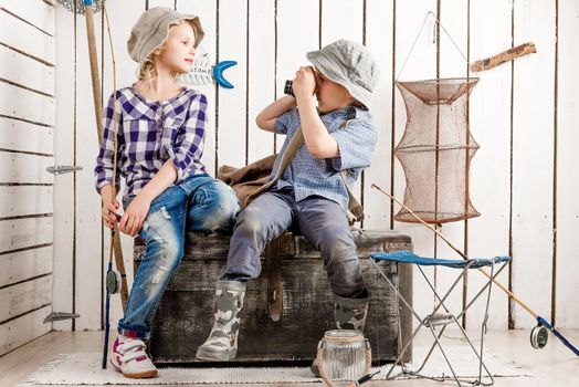 little boy taking picture of cute little girl sitting on big old chest