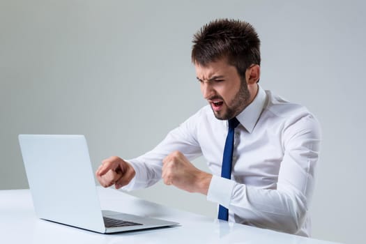 the young man is nervous and poke a finger. It uses a computer while sitting at a table. Office clothing