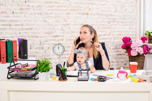 Family Business - telecommute Businesswoman and mother with kid is making a phone call. At the workplace, together with a small child