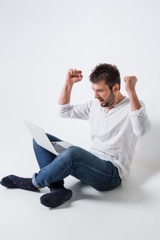 a young man in casual clothes working on a laptop. glad hands up