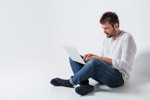 a young man in casual clothes working on a laptop.