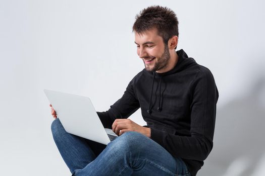 a young man in casual clothes working on a laptop. joyful looking at laptop smiling