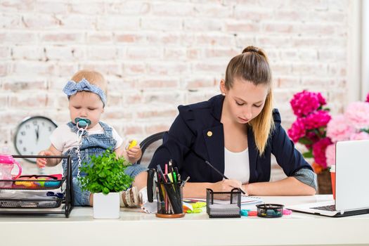 Mom and businesswoman working with laptop computer at home and playing with her baby girl. Horizontal shape, front view, waist up