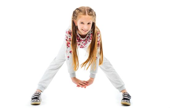 Little girl do forward bend exercise in grey sportwear, isolated on white background. Healthy lifestyle