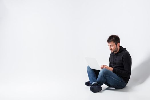 a young man in casual clothes working on a laptop.