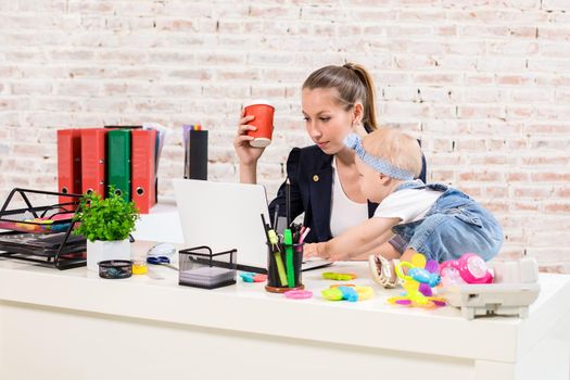 Businesswoman mother woman with a daughter working at the computer. At the workplace, together with a small child