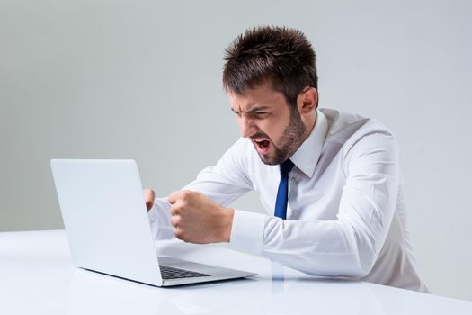 the young man is nervous and has a laptop. It uses a computer while sitting at a table. Office clothing