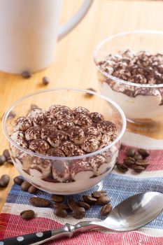 Tiramisu dessert in a glass cup on wooden table close up