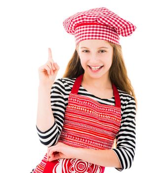 Girl in red kitchen apron and chef hat pointing up isolated on white background