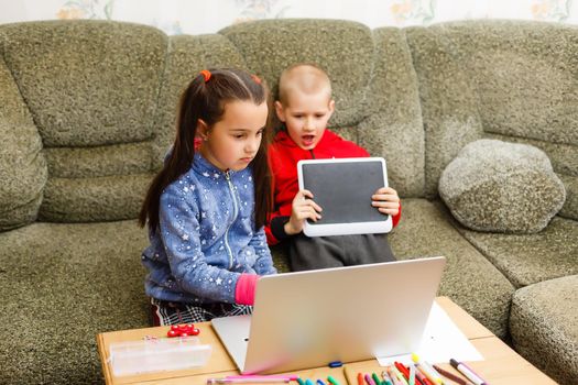 Distance learning online education. school boy and girl studying at home with laptop notebook and doing homework. Sitting at a table