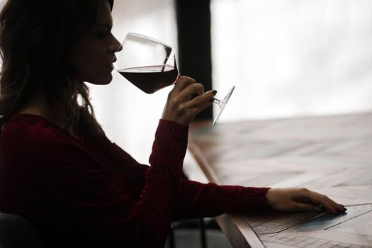 Young woman drinks red wine from a glass