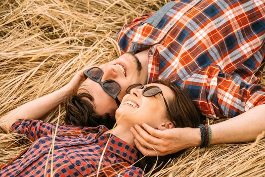 Happy couple in love is lying on the dry grass, top view