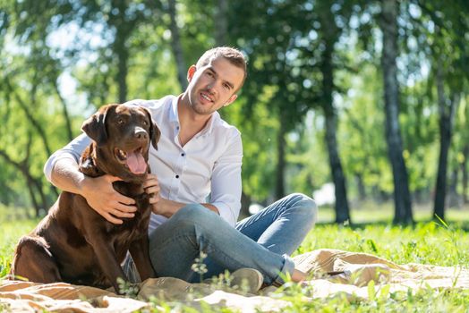 Young man hugs a dog. Spending time with friends in the park