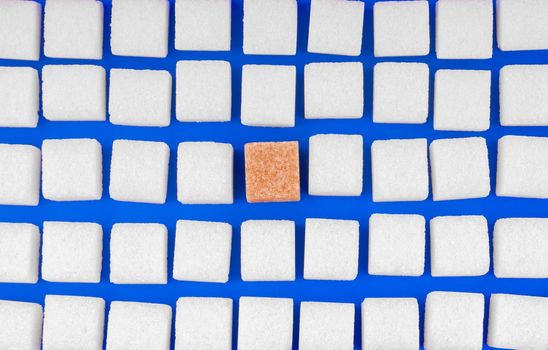 Many cubes of white sugar with one other. Concept not like everyone on blue background top view